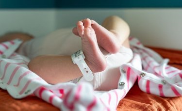 un nourisson est couché, l'image montre ses petits pieds avec le bracelet de la maternité