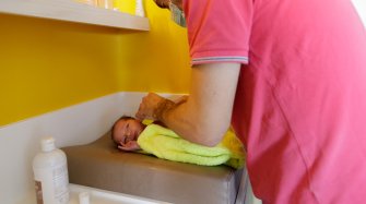 Un jeune papa en train d'habiller son nouveau-né à la maternité des HNO